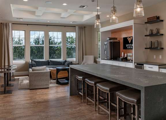 a kitchen with a long counter top and a living room in the background