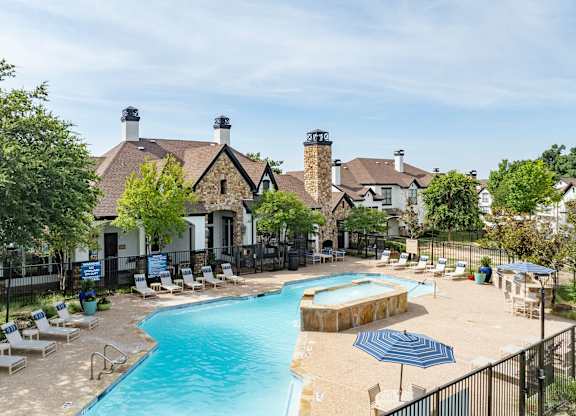 Aerial view of resort-style pool with sundeck and stone clubhouse at Villas of Vista Ridge.