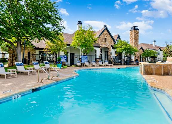 Resort-style swimming pool with expansive deck seating and clubhouse views in Lewisville, TX.