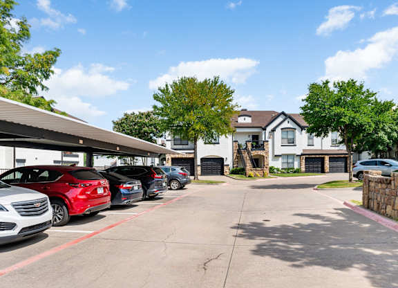 Covered parking area with carports, garages, and landscaped apartment buildings at Villas of Vista Ridge.