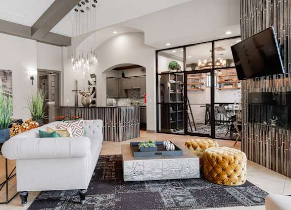 Resident lounge with fireplace, plush seating, coffee table, and adjacent glass-enclosed meeting room.