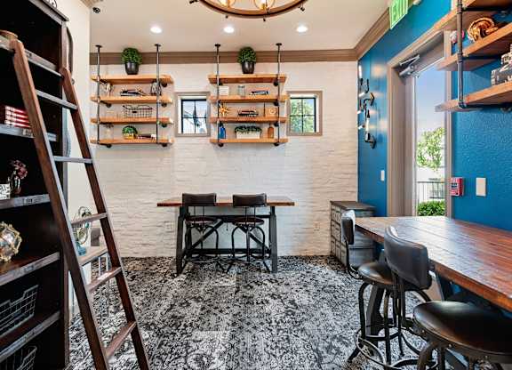 Coworking nook with bar-height desks, floating shelves, and library ladder accent wall.