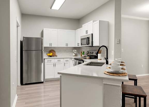 Kitchen with white shaker cabinets, breakfast bar, stainless steel appliances, and open layout.