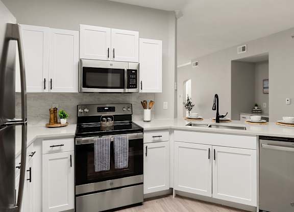 U-shaped kitchen with white cabinets, black fixtures, dishwasher, and peninsula seating.