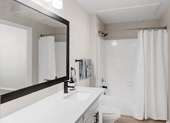 Full bathroom with wide vanity, framed mirror, and tub-shower combination.