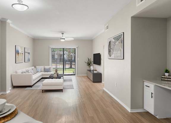 Bright living room with wood-style flooring, crown molding, and sliding glass door to patio.