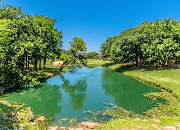 A serene landscape with a river flowing through a lush green park.