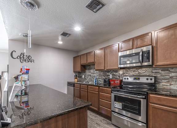 A kitchen with a granite countertop and wooden cabinets.