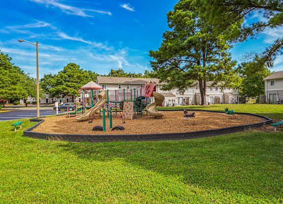 A playground with a slide and swings in a park.