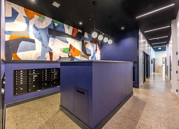 A hallway with a purple reception desk and a colorful mural on the wall.