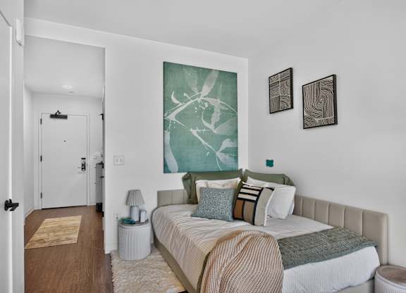 A bedroom with a bed, nightstand, and two wall art pieces at The Indie in Allston.