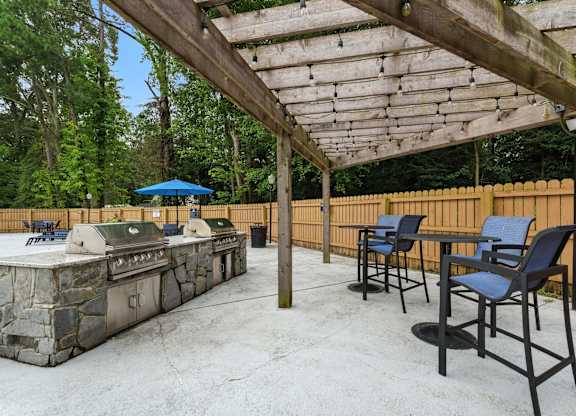 A patio with a grill and chairs under a wooden pergola at The Lawton Townhomes, Virginia, 23832