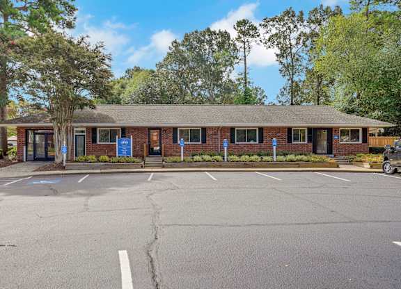 A parking lot in front of a brick building with a blue sign on the door.