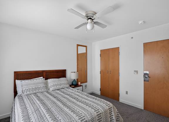 A bedroom with a bed, nightstand, and a ceiling fan.