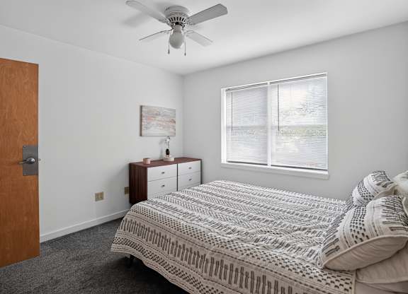 A bedroom with a bed, dresser, and window.