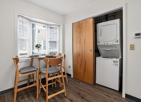 A small dining area with a table and chairs in front of a window.