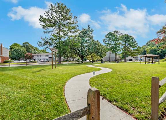 A park with a walking path and a fence.