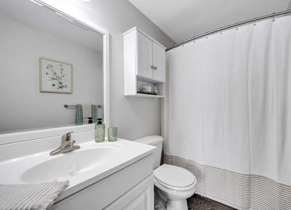 A white bathroom with a toilet, sink, and shower.
