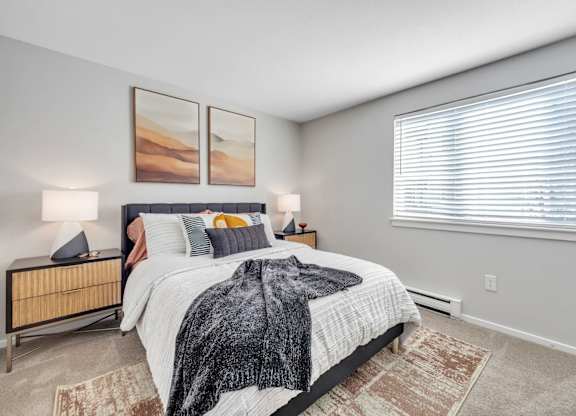 A bedroom with a large bed and two lamps.