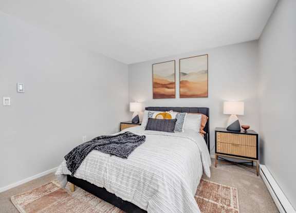 A bedroom with a bed, nightstands, and pictures on the wall.