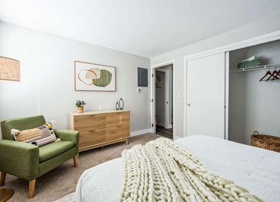A bedroom with a bed, chair, and wardrobe.