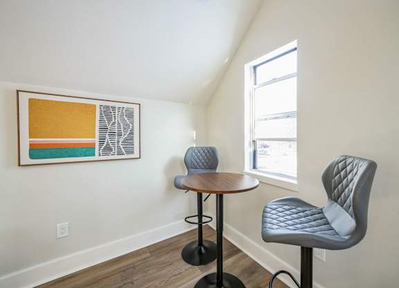 A small table with two chairs in front of a window.