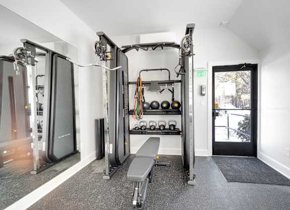 A gym with a bench, weights, and a mirror.