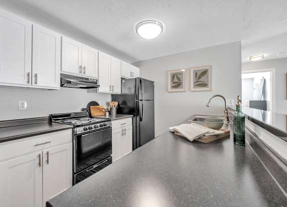 A kitchen with black countertops and white cabinets.