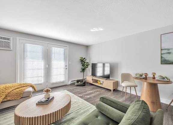 A living room with a green couch, a wooden coffee table, and a television.