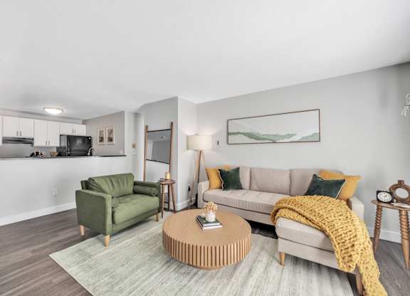 A living room with a green armchair, a beige sofa, and a wooden coffee table.