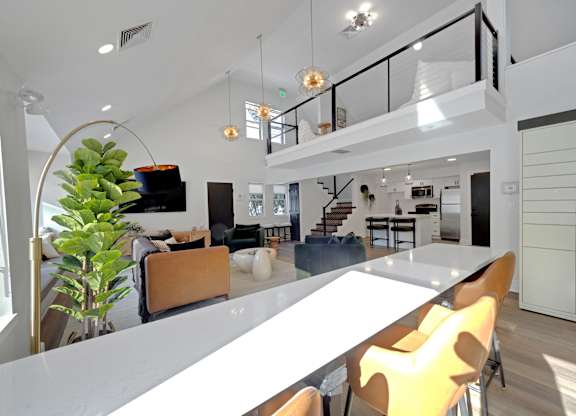 A modern interior with a white table and yellow chairs.