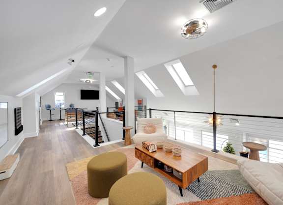A modern living room with a white sofa, a wooden coffee table, and a balcony with a railing.