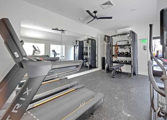 A TRIX treadmill is in the foreground of a well equipped gym.