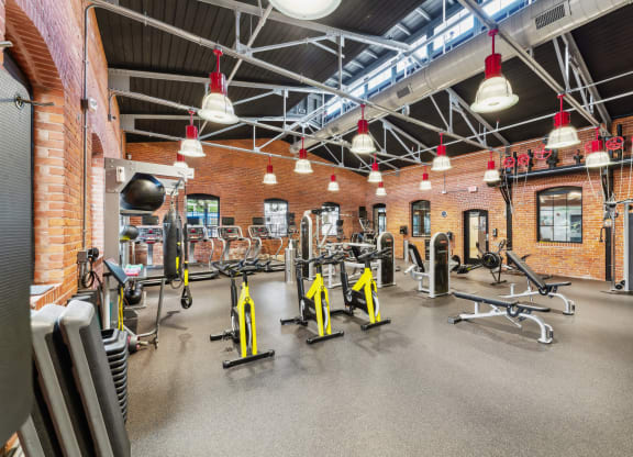 a gym with weights and cardio equipment and brick walls at The Tannery, Connecticut