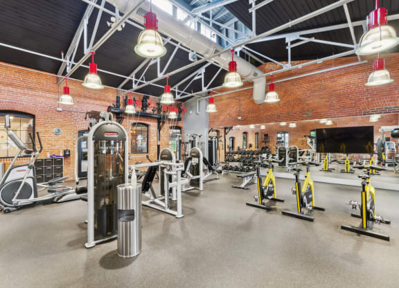 a gym with weights and cardio equipment and a brick wall at The Tannery, Glastonbury