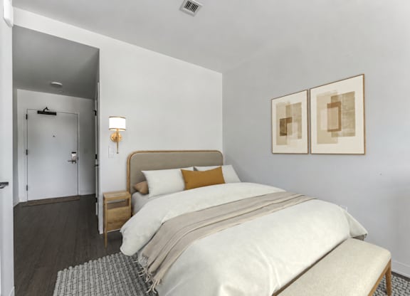 A bedroom with a bed, nightstand, and two framed pictures on the wall.