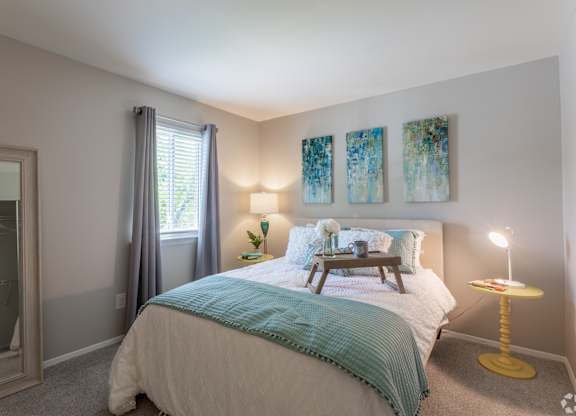 a bedroom with a bed and a nightstand and a window at The Lawton Townhomes, Chesterfield , VA