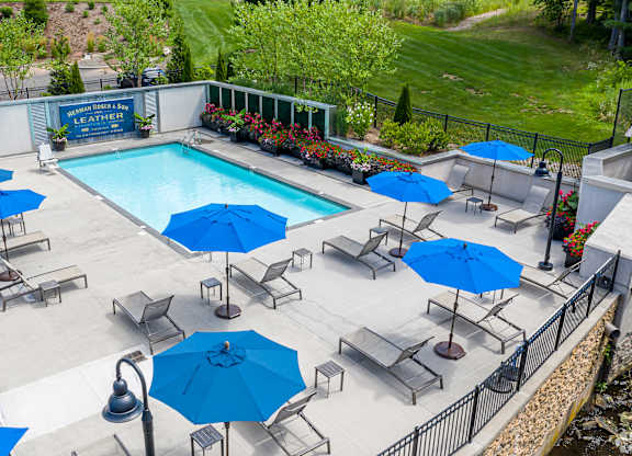 A pool surrounded by blue umbrellas and chairs.