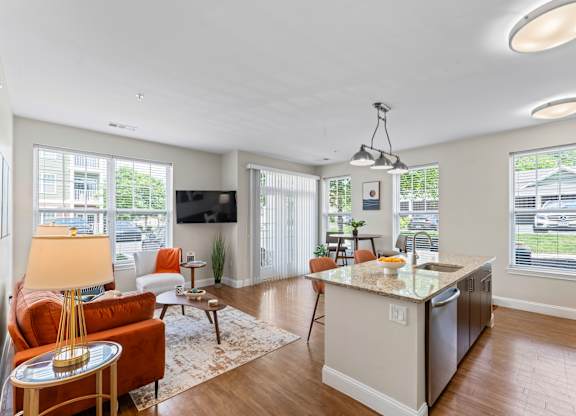 A well-lit kitchen and living room with a large island in the middle.