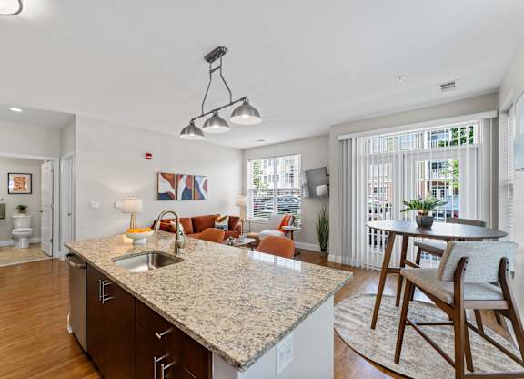 A kitchen with a granite countertop and wooden floors.