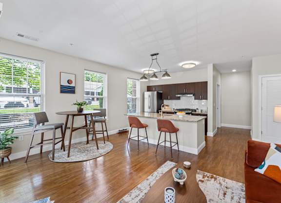 A well-lit, modern kitchen and living room with wooden floors and furniture.