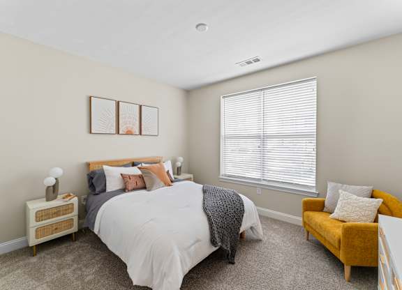 A bedroom with a bed, nightstand, and chair.