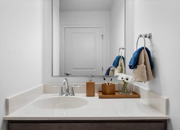 A bathroom sink with a mirror above it and towels hanging on the wall.