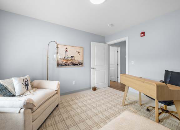 A room with a couch, chair, and desk.