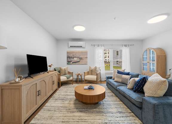 A living room with a blue couch, a wooden cabinet, and a flat screen TV.