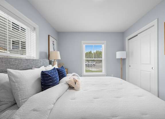 A bedroom with a large bed and a window overlooking a grassy area.