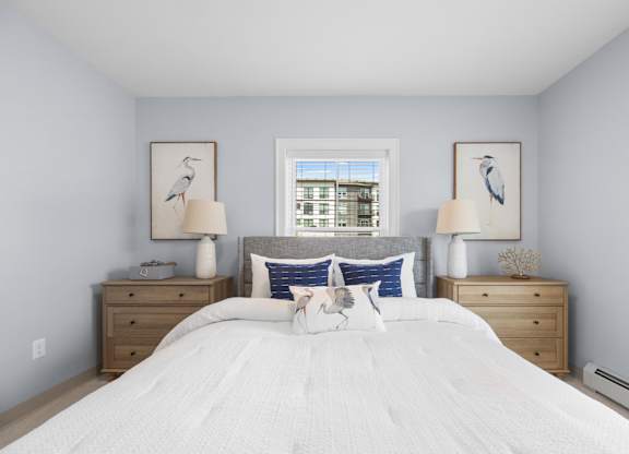 A bedroom with a large bed, two nightstands, and two framed pictures on the wall.