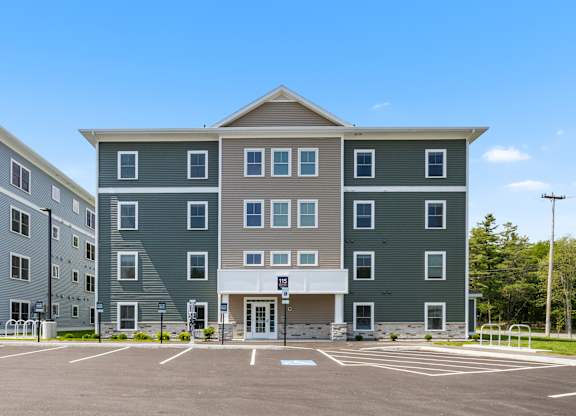 A large grey building with a parking lot in front.