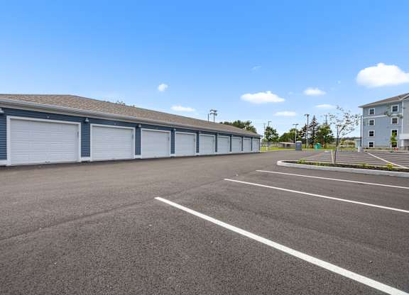 A large, empty parking lot with garage bays in the background.