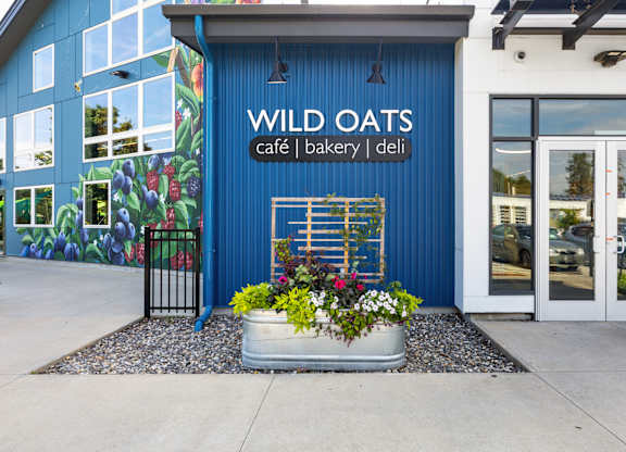 A blue building with a mural of fruit on the side and a sign that says Wild Oats.